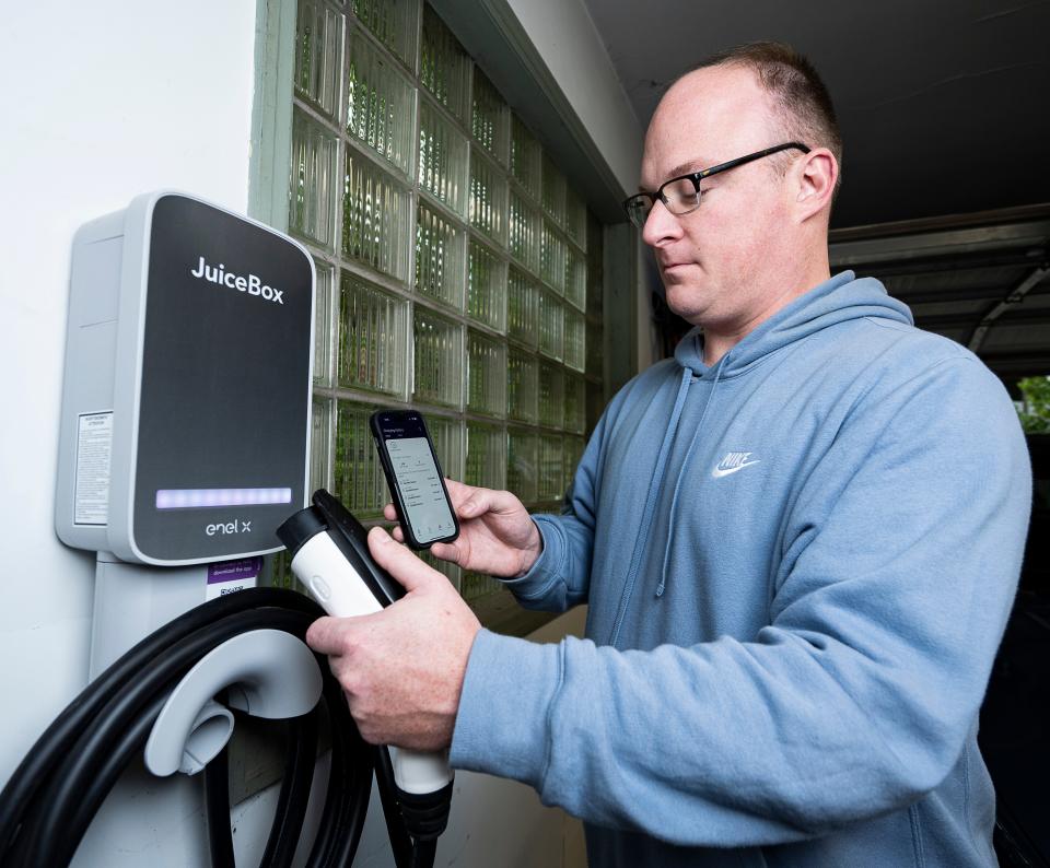 Andrew Tilley uses the EV charging app on his phone to check his charging history. Tilley bought the charger through a program offered by We Energies that offers lower-cost electricity to customers who charge their vehicles at times of low demand.