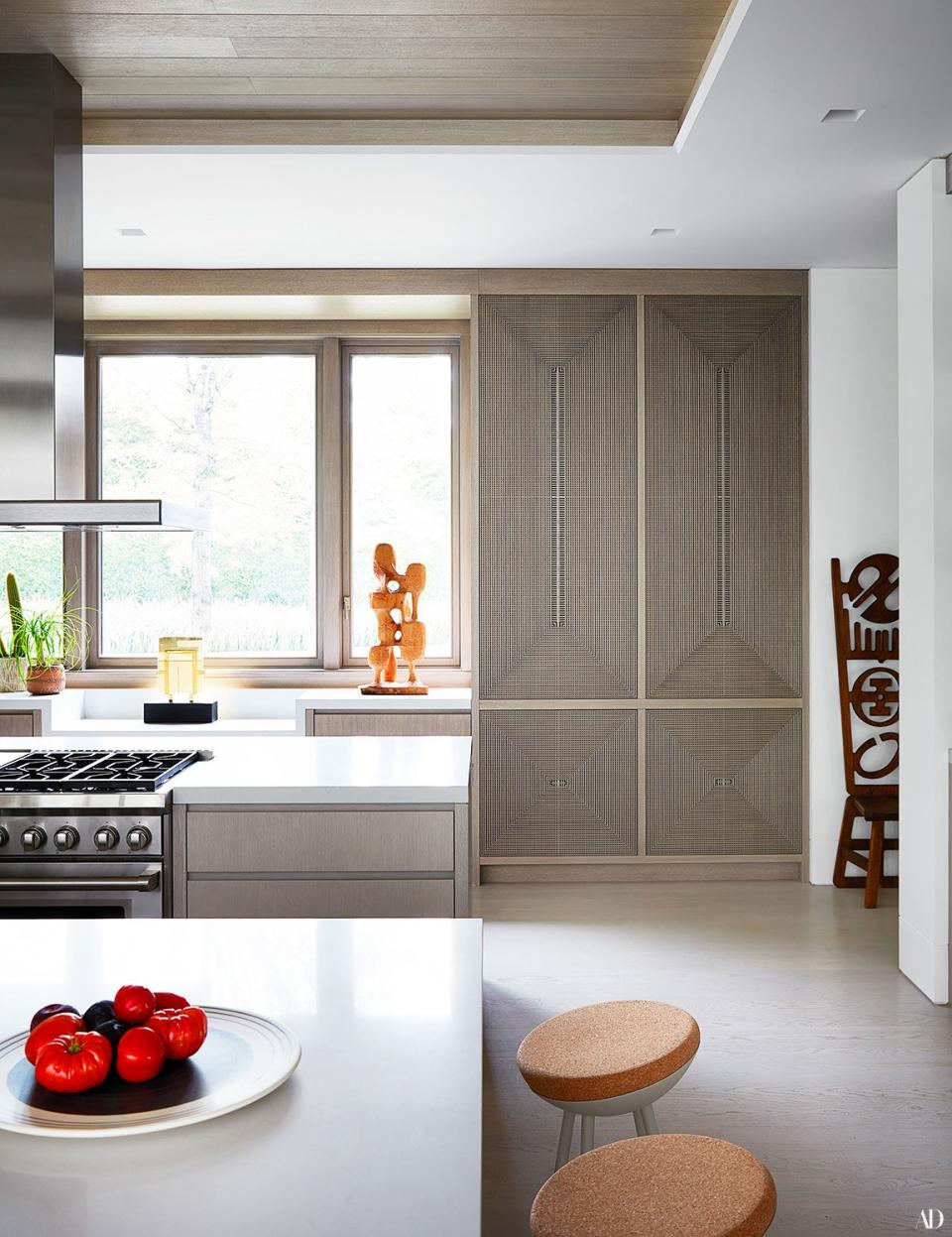 Sculptures by Yolande Batteau (left) and Uchigawa Ni Hisomu Mono sit atop the kitchen counter. Custom cabinet doors by Kelly Behun Studio; Thermador hood and Wolf range.