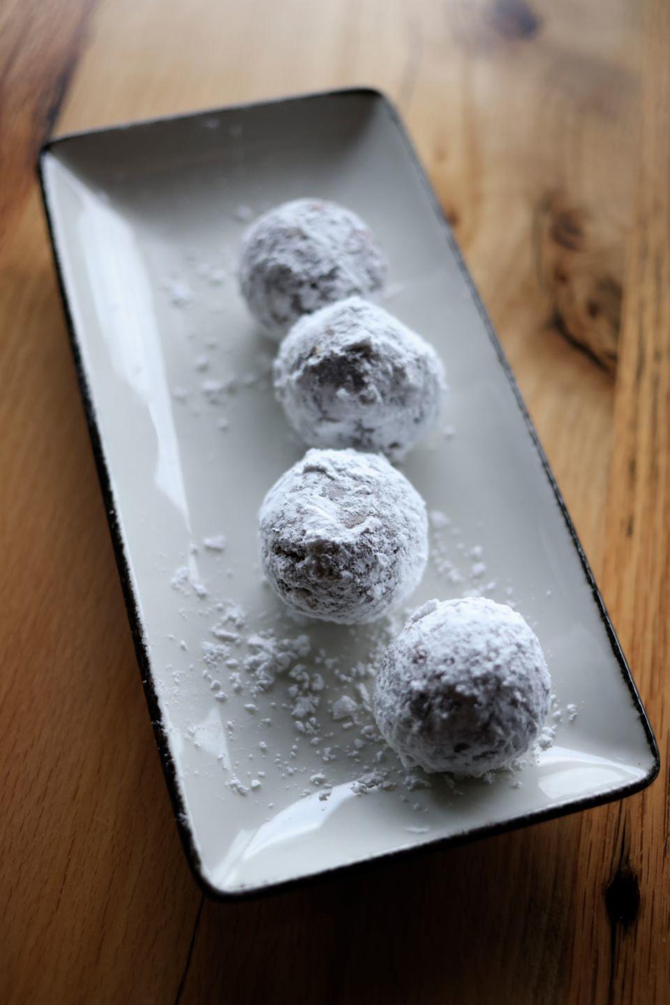 tray of chocolate bourbon balls rolled in powdered sugar on a wooden table