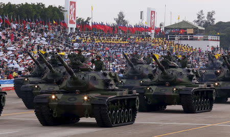 Military personnel salute as they stand on M60A3 main battle tanks displayed during the annual Han Kuang military exercise in an army base in Hsinchu, northern Taiwan, July 4, 2015. REUTERS/Patrick Lin