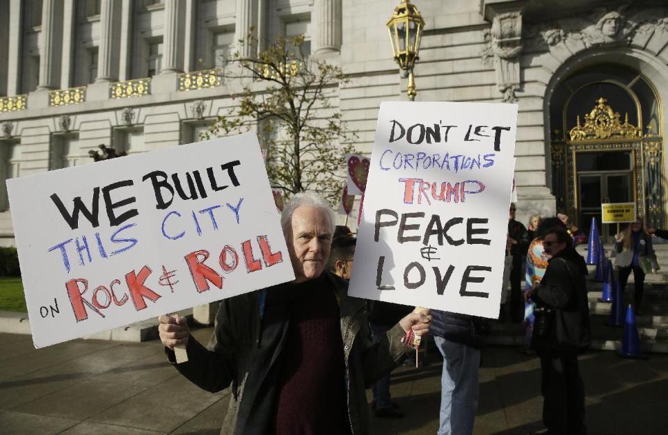 Charles Cowles holds up a pair of signs in support of a Summer of Love anniversary concert during a protest outside City Hall Thursday, Feb. 16, 2017, in San Francisco. The show might still go on but a concert planned to mark the 50th anniversary of the Summer of Love has hit another major bureaucratic hurdle. San Francisco's Recreation and Park Commission on Thursday upheld its decision earlier this month to deny a permit for the concert. (AP Photo/Eric Risberg)