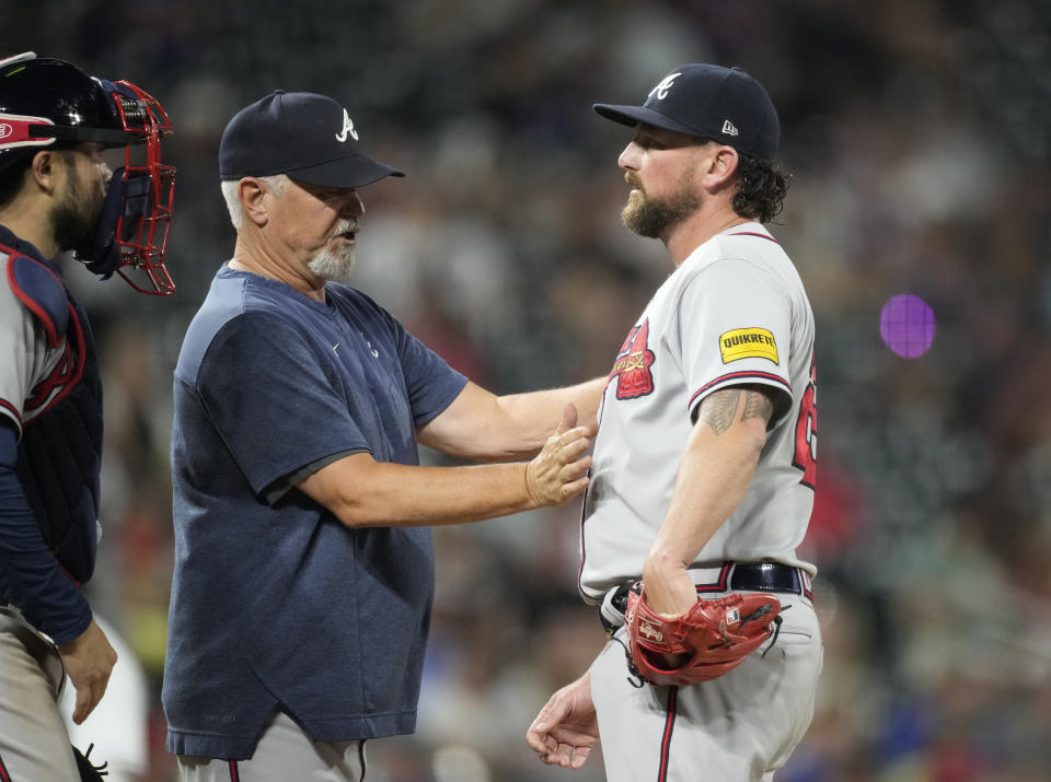 Atlanta Braves pitching coach Rick Kranitz, left, confers with relief pitcher Kirby Yates, who had walked Colorado Rockies' Nolan Jones during the eighth inning of a baseball game Wednesday, Aug. 30, 2023, in Denver. (AP Photo/David Zalubowski)