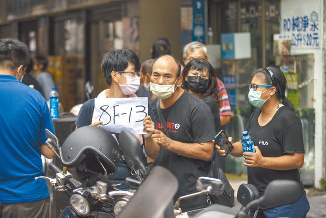 城中城大火，戴姓女子（左二）從台南趕回，焦急在對街手持標示父母親房號的告示牌，希望救難人員找到她的父母，無奈最後等到的是痛心的答案。（袁庭堯攝）