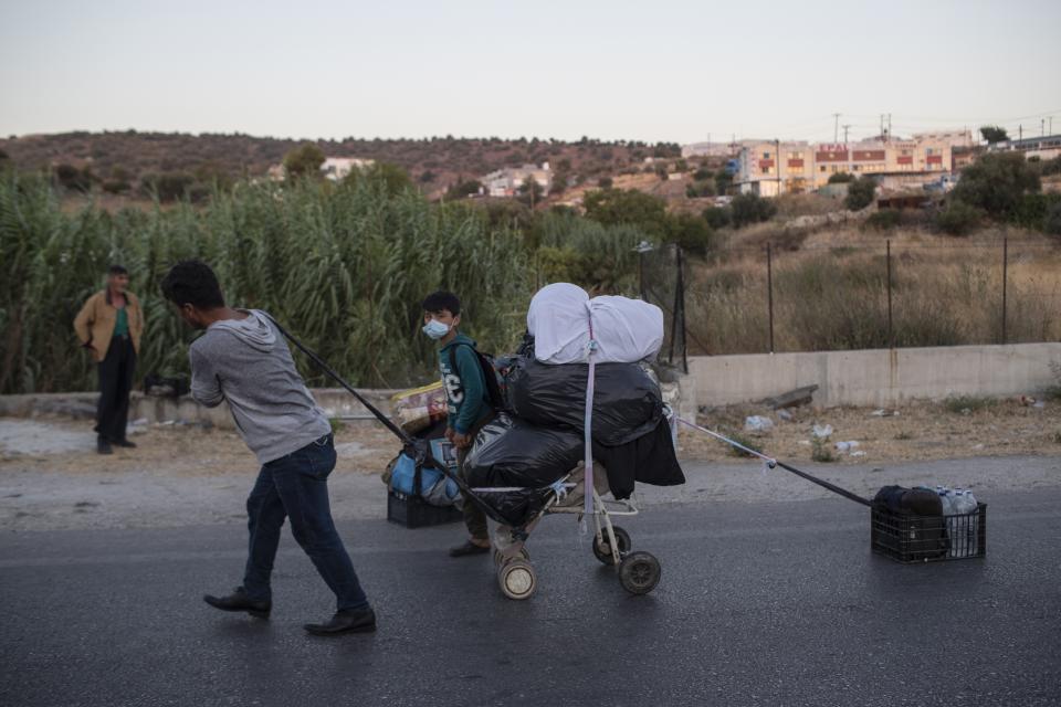 A migrant pulls his belongings on the northeastern island of Lesbos, Greece, Friday, Sept. 11, 2020. The Greek government says thousands of migrants left homeless after fires gutted a sprawling refugee camp on the island of Lesbos will not be allowed to travel to mainland Greece. (AP Photo/Petros Giannakouris)