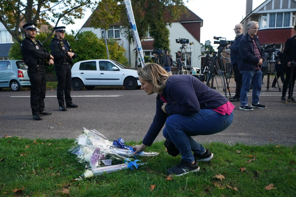 A woman lays flowers near the Belfairs Methodist Church in Eastwood Road North, where Conservative MP Sir David Amess was stabbed several times at a constituency surgery, in Leigh-on-Sea, Essex, England, Friday, Oct. 15, 2021. British Conservative lawmaker David Amess has died after being stabbed Friday during a meeting with constituents at a church in eastern England. A 25-year-old man has been arrested. (Yui Mok/PA via AP)