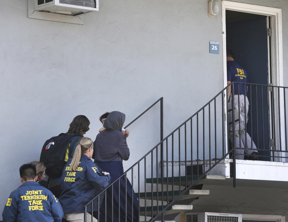 FILE - In this Aug. 15, 2018, file photo, a woman carrying a child is escorted by authorities to an apartment following the arrest of a 45-year-old Iraqi refugee, Omar Ameen in Sacramento, Calif. A federal judge in California refused Wednesday, April 21, 2021, to allow the extradition to Iraq of Ameen, accused of killing for the Islamic State, saying cellphone evidence shows he was in Turkey at the time of the slaying. The U.S. Justice Department has tried since 2018 to return Omar Abdulsattar Ameen to Iraq under a treaty with that nation. (AP Photo/Rich Pedroncelli, File)