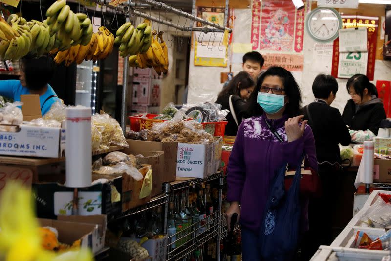 A woman wears a face mask shopping at a market in the Chinatown section of San Francisco, California