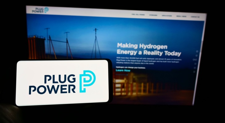 Person holding cellphone with logo of American hydrogen fuel cell company Plug Power Inc on screen in front of web page Focus on phone display