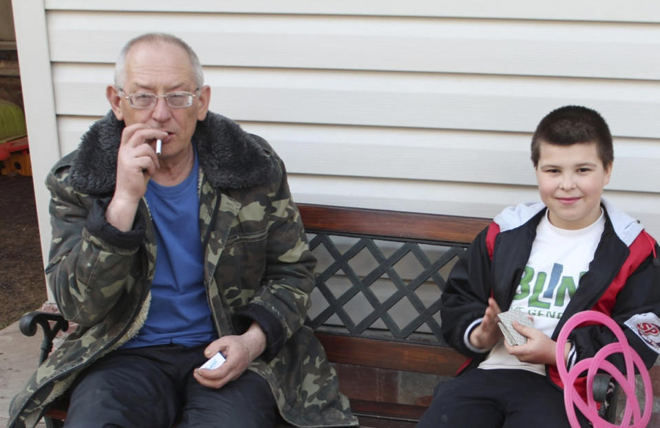 In this 2013 photo provided by the Vlasenko family, Pavlo Vlasenko sits with his young grandson, Dmytro Chaplyhin, who was known as Dima. Dima was one of at least nine men Russian soldiers picked up during a March 4, 2022, sweep of Bucha, Ukraine, and executed at their headquarters at 144 Yablunska Street. Russians returned a few weeks later and found a military cap in the house. They beat Pavlo Vlasenko to death, then set his body on fire in the yard. (Vlasenko family via AP)