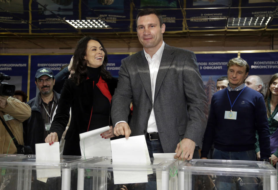 Chairman of the Ukrainian democratic opposition Ukrainian Democratic Alliance for Reform Party and former boxing champion Vitali Klitschko, centre right, and his wife Natalia cast their ballots, at a polling station during parliamentary elections in Kiev, Ukraine, Sunday, Oct. 28, 2012. Ukrainians are electing a parliament on Sunday in a crucial vote tainted by the jailing of top opposition leader Yulia Tymoshenko and fears of election fraud. (AP Photo/Efrem Lukatsky)
