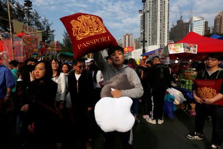 FILE PHOTO: A vendor sells cushions depicting the Apple Inc logo and a British passport inside a Lunar New Year market at Hong Kong's Victoria Park February 17, 2015. REUTERS/Bobby Yip/File Photo