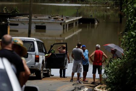 Local residents look at the flooded houses close to the dam of the Guajataca lake. REUTERS/Carlos Garcia Rawlins