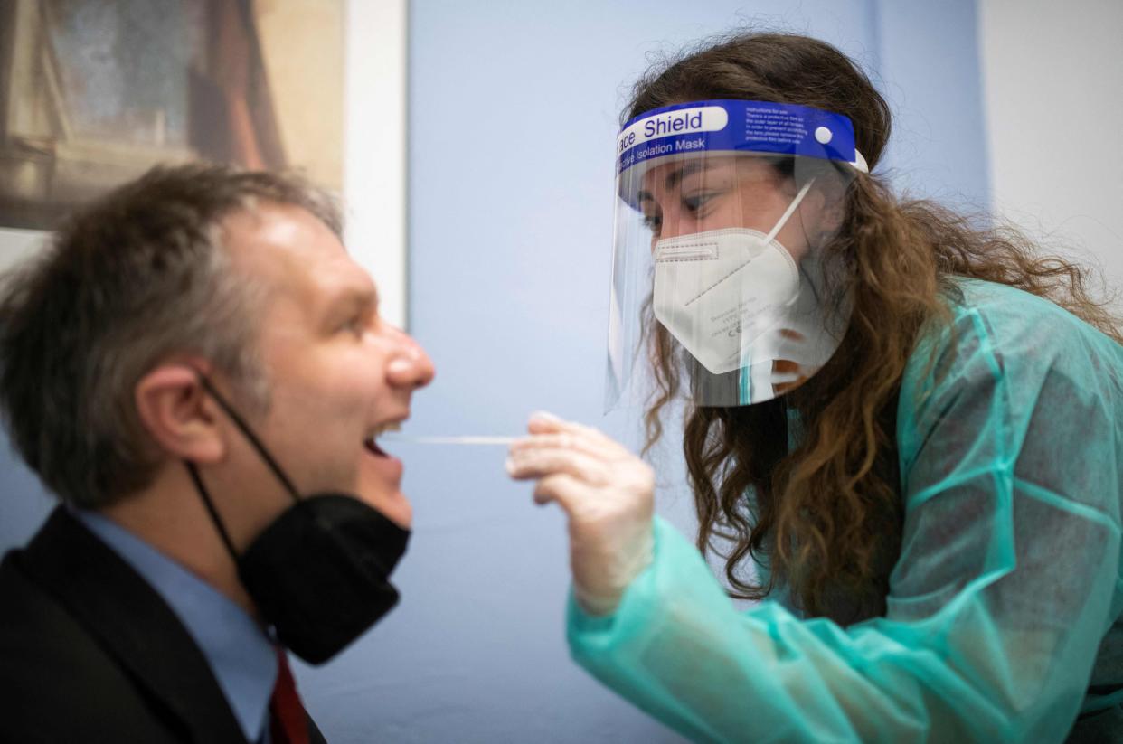 Employee Melissa demonstrates how she takes a swab sample for a rapid antigen test on pharmacist Christian Fehske (L) at a Corona test center in a specially created room next to the 'Rathaus' pharmacy in Hagen, western Germany on March 10, 2021, during the ongoing coronavirus (Covid-19) pandemic.