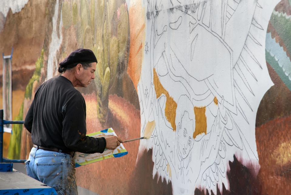 Local artist Carlos Lopez works on a portion of a 24 ft. by 47 ft. mural of Our Lady of Guadalupe on the east exterior wall of St. Gertrude's Church gymnasium in Stockton on Dec. 8, 2017. Lopez is repainting the original mural, done by artist Greg Custodio in 1982, which had faded over the years. Lopez says he's repainting it with his own flourishes. 