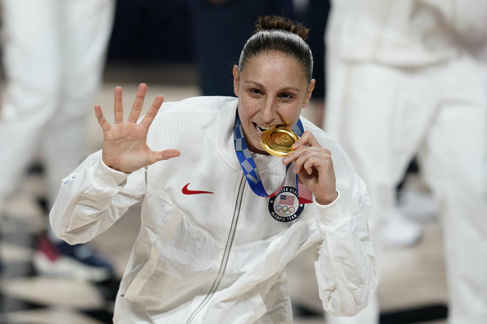 United States's Diana Taurasi bites her gold medal during the medal ceremony for women's basketball at the 2020 Summer Olympics, Sunday, Aug. 8, 2021, in Saitama, Japan. (AP Photo/Charlie Neibergall)