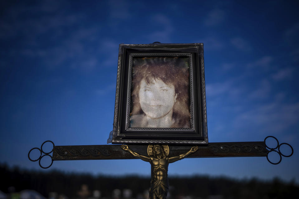 A faded portrait of Natalya Savlukova, 61, sits on her grave at a cemetery in Irpin, Ukraine, on the outskirts of Kyiv, on Friday, Feb. 10, 2023. Savlukova lived alone. She had terminal cancer but no one could say how she died, only that it had been under occupation. She was buried on March 3, 2022. (AP Photo/Emilio Morenatti)