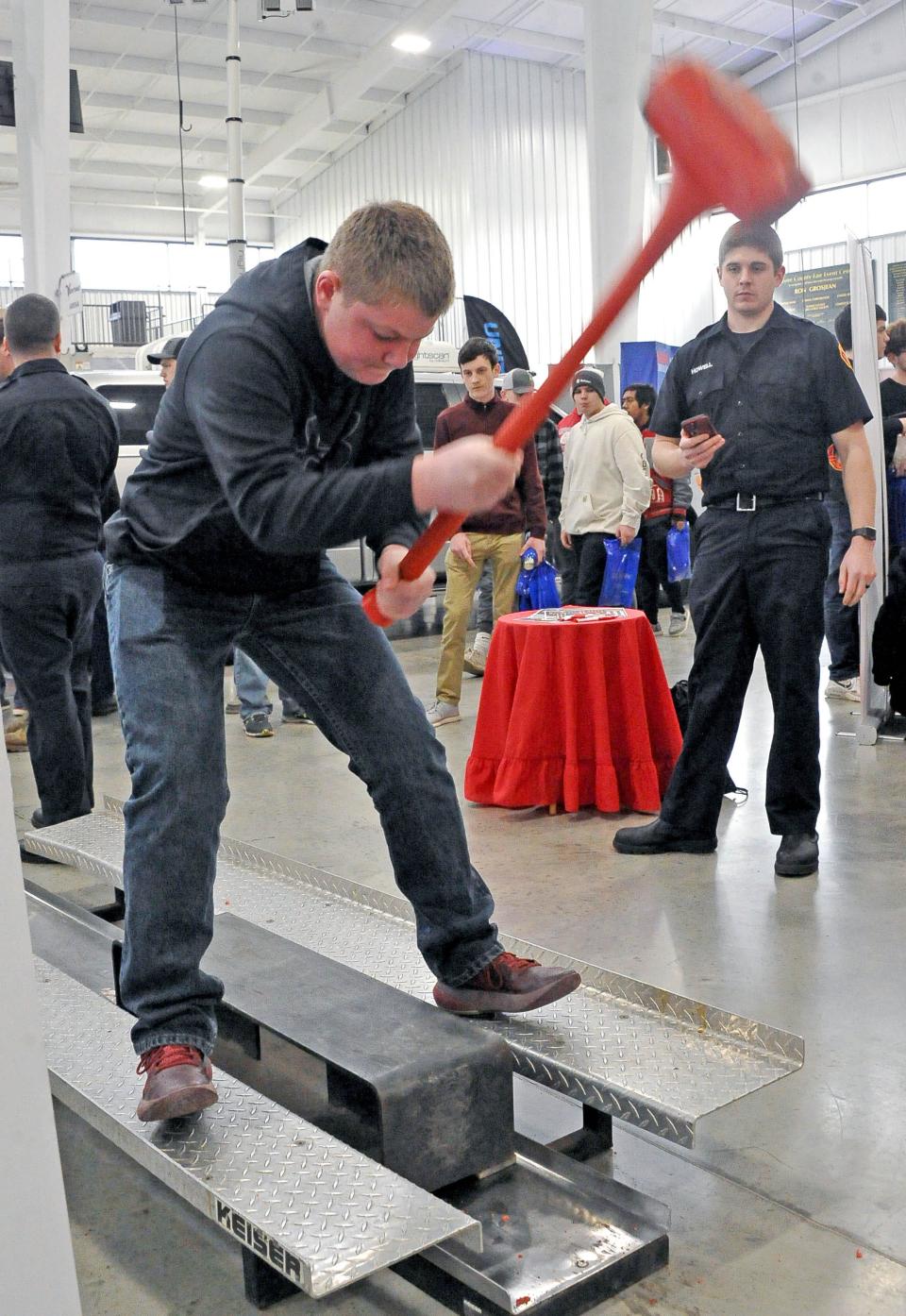 Brent Underwood of Norwayne High School uses a sledge hammer to move a weight in a timed activity at the Ashland Fire Department booth at JA Inspire.