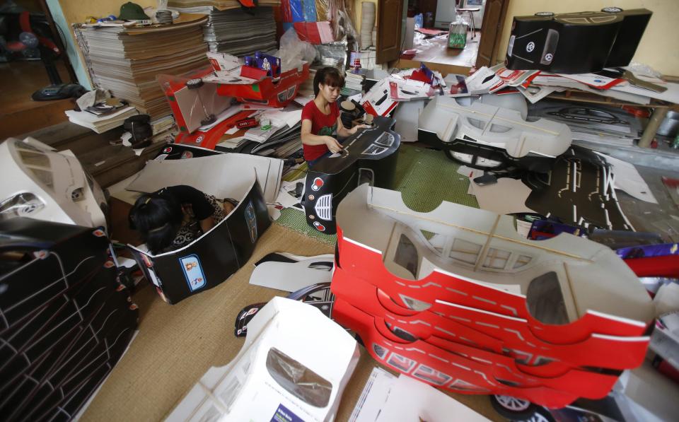 Women make paper replicas of cars to be sold for the Vu Lan Festival at Dong Ho village, outside Hanoi