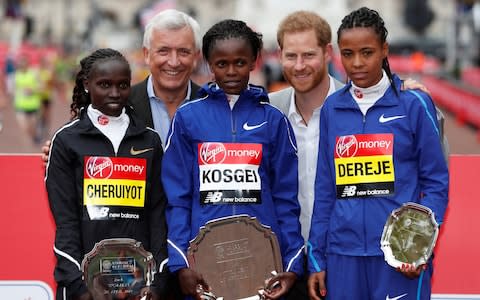 Kenya's Brigid Kosgei celebrates winning the women's elite race with the trophy as she poses with Britain's Prince Harry  - Credit: &nbsp;REUTERS/Paul Childs