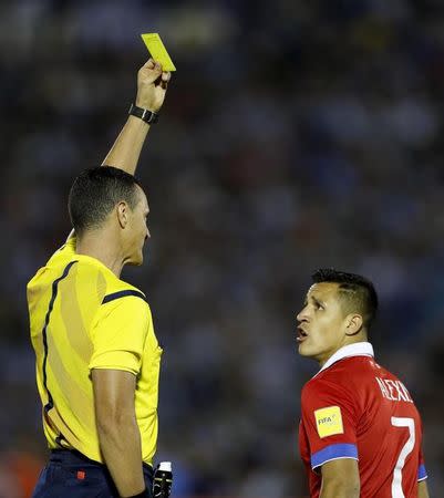 Referee Wilmar Roldan presents a yellow card to Chile's Alexis Sanchez during their 2018 World Cup qualifying soccer match against Uruguay at Centenario stadium in Montevideo, November 17, 2015. REUTERS/Andres Stapff