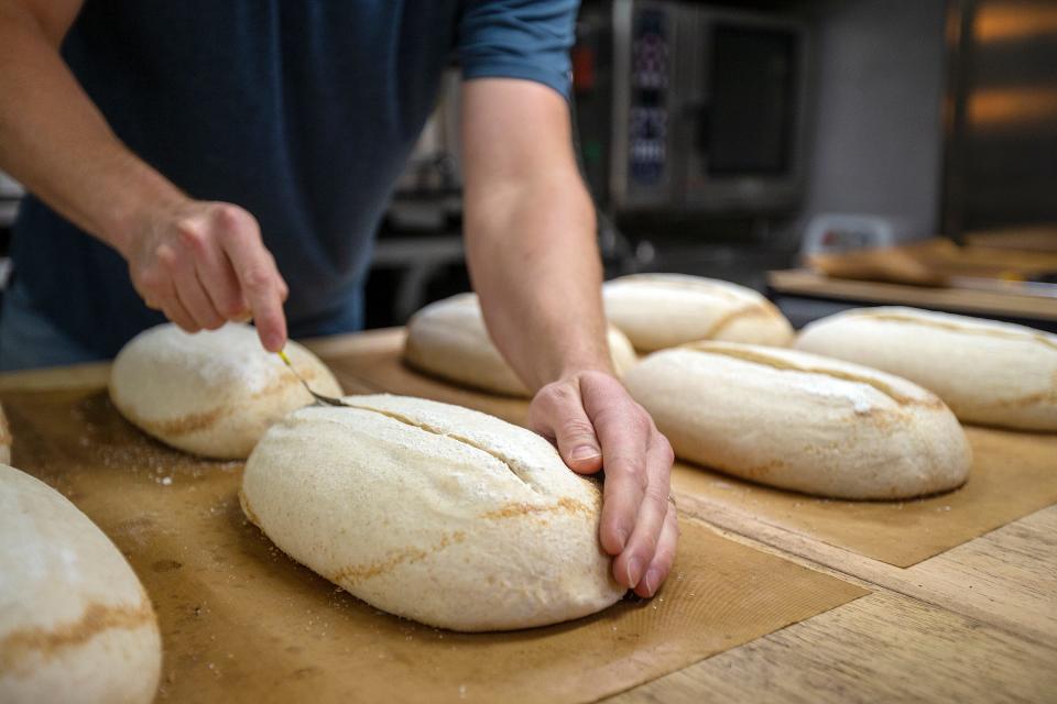 Travis Coatney, owner of Benchmark Breads in Atlantic Highlands, scores loaves of sourdough bread before baking.