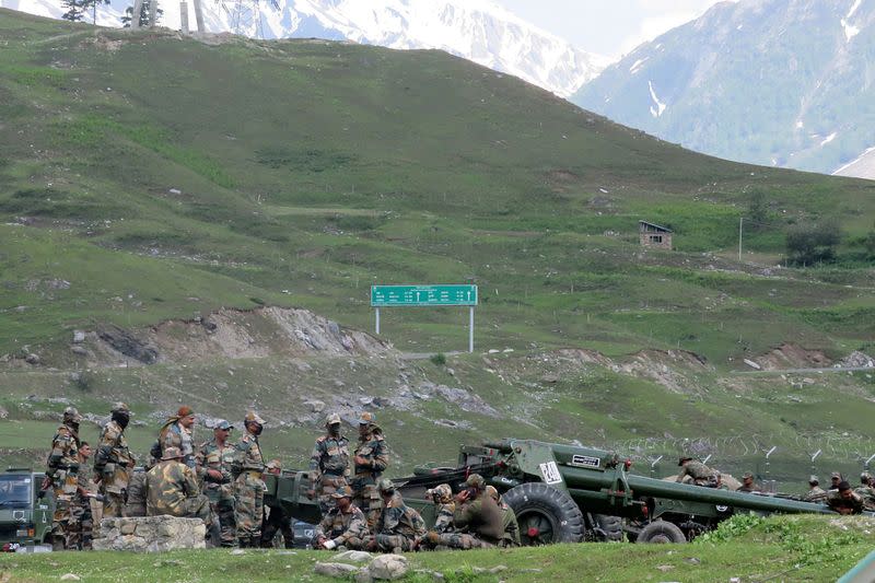 Indian army soldiers rest next to artillery guns at a makeshift transit camp before heading to Ladakh, near Baltal