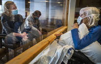 Carla Gillespie with her son Dylan visited her mother, Evelyn Solberg at the Jones-Harrison Residence in Minneapolis, Monday, Oct. 12, 2020. It was the first time families have been allowed to visit residents inside nursing homes while masked up and behind a plastic shield since March. (Richard Tsong-Taatarii/Star Tribune via AP)