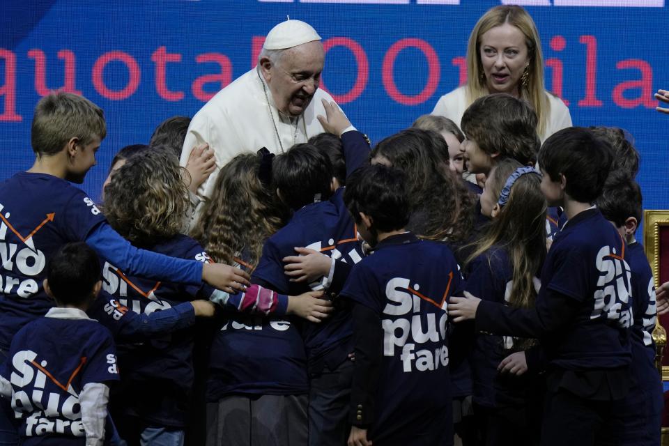 Pope Francis greets kids at the end of a conference to discuss the "demographic winter" and "empty cribs" problem Italy is facing. Panel introduced by Gigi De Palo, president of Birth Rate Foundation, at Auditorium della Conciliazione, in Rome, Friday, May 12, 2023. (AP Photo/Alessandra Tarantino)