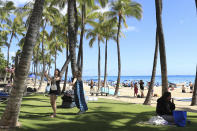 Two people take pictures on Waikiki Beach, Thursday, June, 23, 2022 in Honolulu. In a major expansion of gun rights after a series of mass shootings, the Supreme Court said Thursday that Americans have a right to carry firearms in public for self-defense.