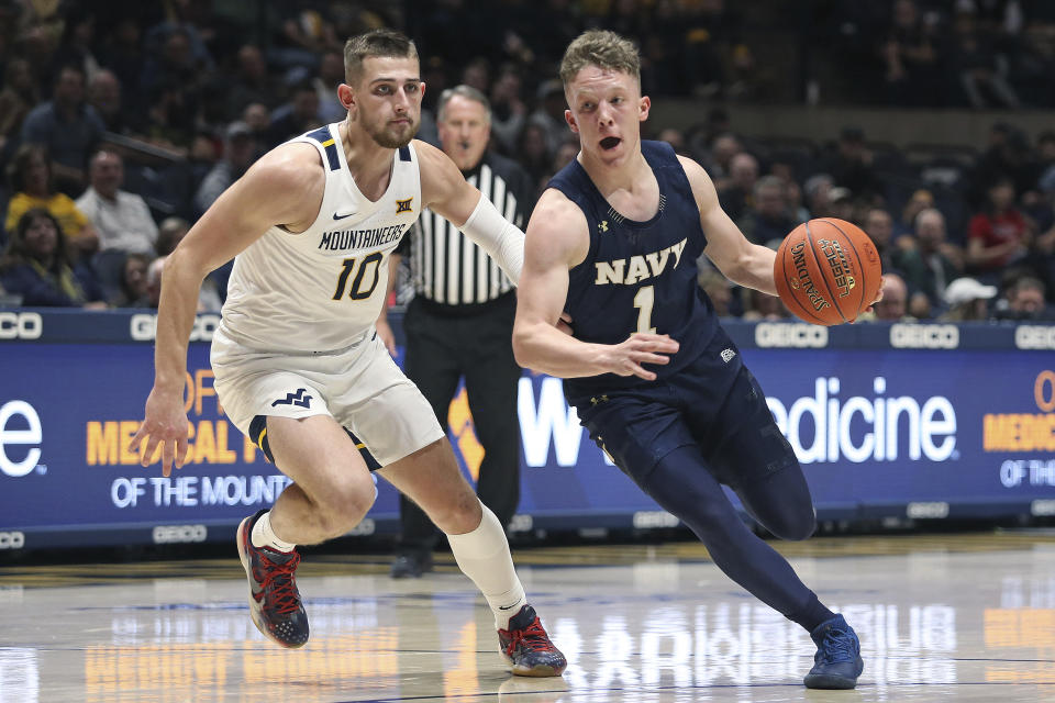 Navy guard Austin Benigni (1) is defended by West Virginia guard Erik Stevenson (10) during the first half of an NCAA college basketball game in Morgantown, W.Va., Wednesday, Dec. 7, 2022. (AP Photo/Kathleen Batten)