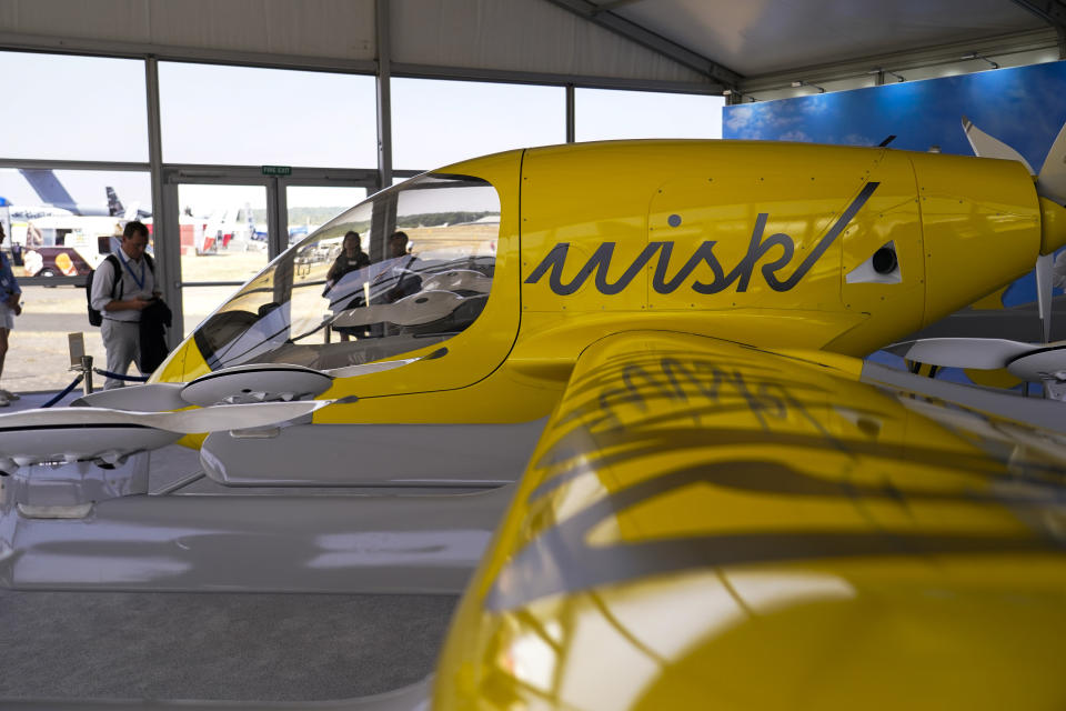 Visitors look at a model of the Wisk Aero autonomous aircraft, at the Farnborough Air Show fair in Farnborough, England, Tuesday, July 19, 2022. Some 1191 exhibitors from around the world show their newest developments in Future Flight, Space, Defence, Innovation, Sustainability and Workforce from July 18th until July 22, 2022.(AP Photo/Alberto Pezzali)