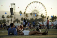 FILE - In this Sunday, April 13, 2014 file photo, Coachella festival goers Justin Gibbs and Olivia Hansen of Los Angeles relax on the Empire Polo Field during the third day of the 2014 Coachella Music and Arts Festival in Indio, Calif. The Coachella crowd may be there to listen to music under the hot desert sun, but the retailers are there for the celebs and the crowd, which is young, hip and with money to spend. (Photo by Chris Pizzello/Invision/AP, file)