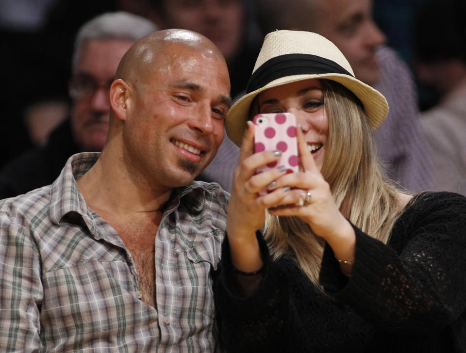 In this March 23, 2012, file photo, Actress Kaley Cuoco uses a mobile phone as she sits with an unidentified man courtside at the NBA basketball game between the Portland Trail Blazers and Los Angeles Lakers in Los Angeles. The Electronic Entertainment Expo conference, which officially starts Tuesday, June 5, 2012, in Los Angeles, is still the place to showcase all the big blockbusters and flashy console games, but games for smartphones and tablets are increasingly in the minds of game developers. (AP Photo/Danny Moloshok, File)