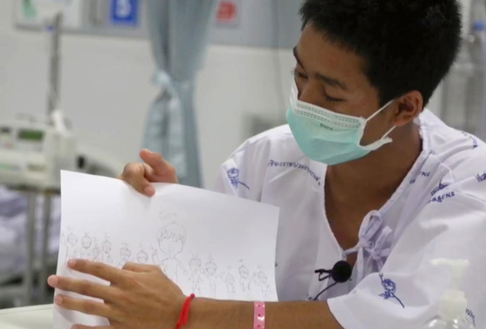 Adul Samon, one of the 12 boys rescued from the Tham Luang cave, speaks from hospital showing a drawing of himself and his teammates. Source: AAP