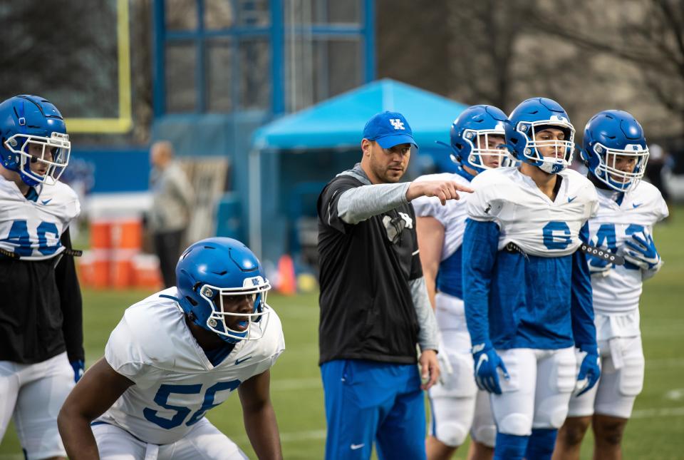 Kentucky inside linebackers coach Jon Sumrall delivers instructions over the shoulder of sophomore linebacker D'Eryk Jackson during spring football practice in 2021.