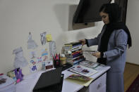 An Afghan university student Bahija Aman, 21, 3rd year anthropology major, arranges books on her home desk, as she prepares to go back to her university in Kabul, Afghanistan, Thursday, Feb. 24, 2022. Kabul University, among Afghanistan’s oldest and most revered institutions of higher education, reopened Saturday six months after the Taliban retook the country. There were new restrictions in place, however, including gender segregation and mandatory Islamic dress. (AP Photo/Hussein Malla)