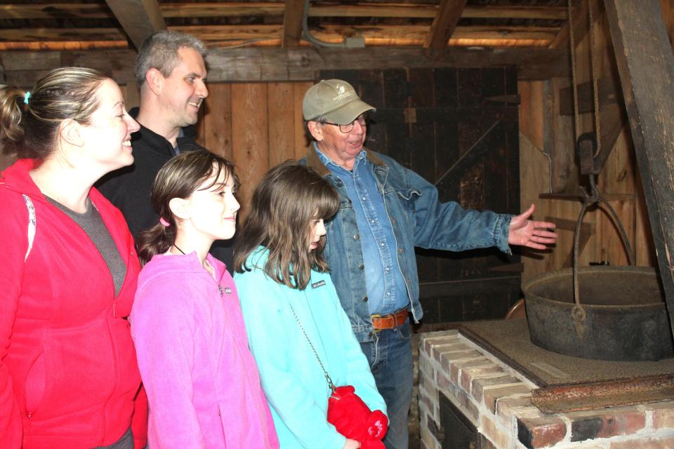 Bob Shively, a volunteer for the Historical and Genealogical Society of Somerset County, shows Alex and Becky Hartos of Pittsburgh and their children, Elizabeth, 12, and Katelynn, 10, the 1860s maple camp on the grounds of the society during last weekend's Maple Tour.