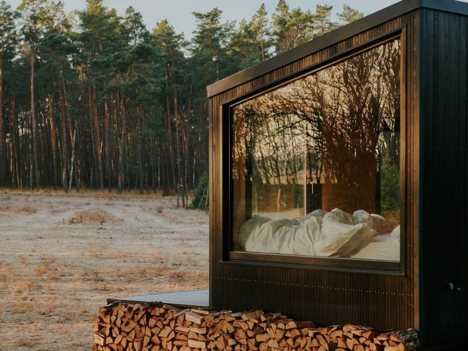 A close up of a Raus cabin in nature surrounded by trees and open fields.