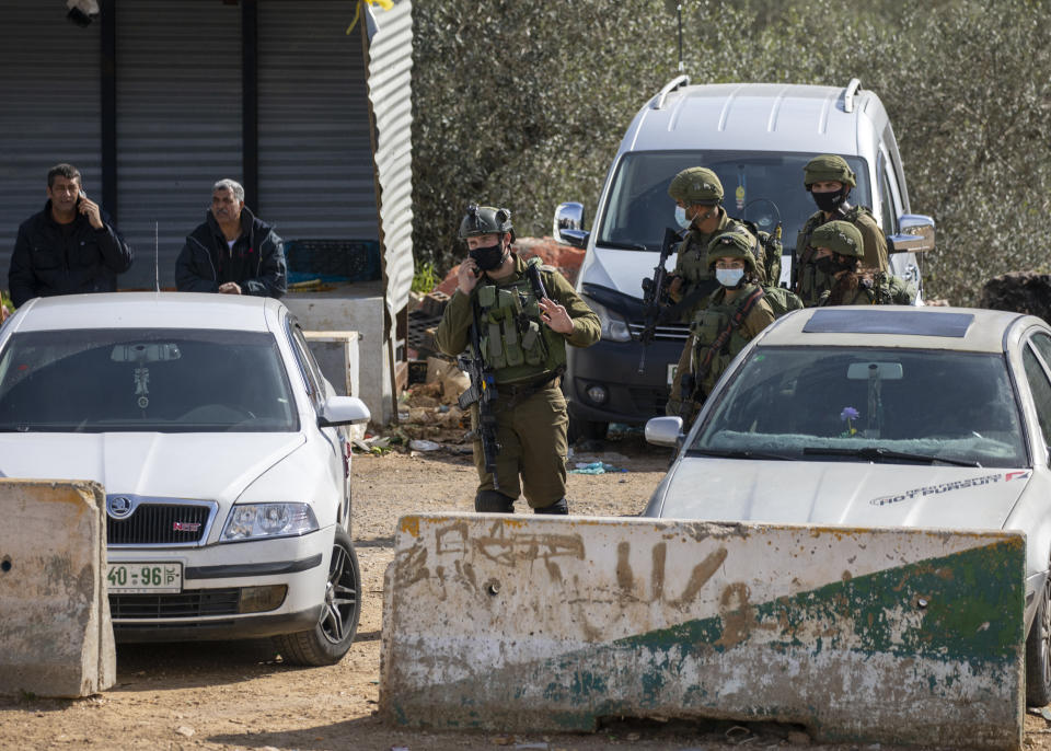 Israeli soldiers secure the area where the military said troops killed a Palestinian man suspected of trying to attack soldiers, at a West Bank junction near the joint Israeli-Palestinian industrial zone of Barkan, Tuesday, Jan. 26, 2021. (AP Photo/Ariel Schalit)