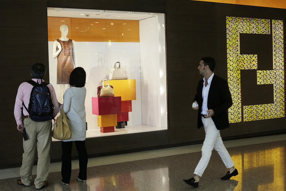 Shoppers look at the window display of a Fendi store Wednesday, June 13, 2012, in Shanghai, China. Chinese consumers can afford to splash out more on higher quality products, but also expect better value for money than in the past, according to a study by the American Chamber of Commerce. (AP Photo/Eugene Hoshiko)