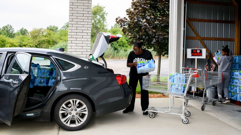 Diana Wiley Washington, 58, works with her daughter in August 2021 to load bottled water in their car for delivery to local seniors as part of an outreach program through their church in Flint, Michigan. - Brittany Greeson/For The Washington Post/Getty Images