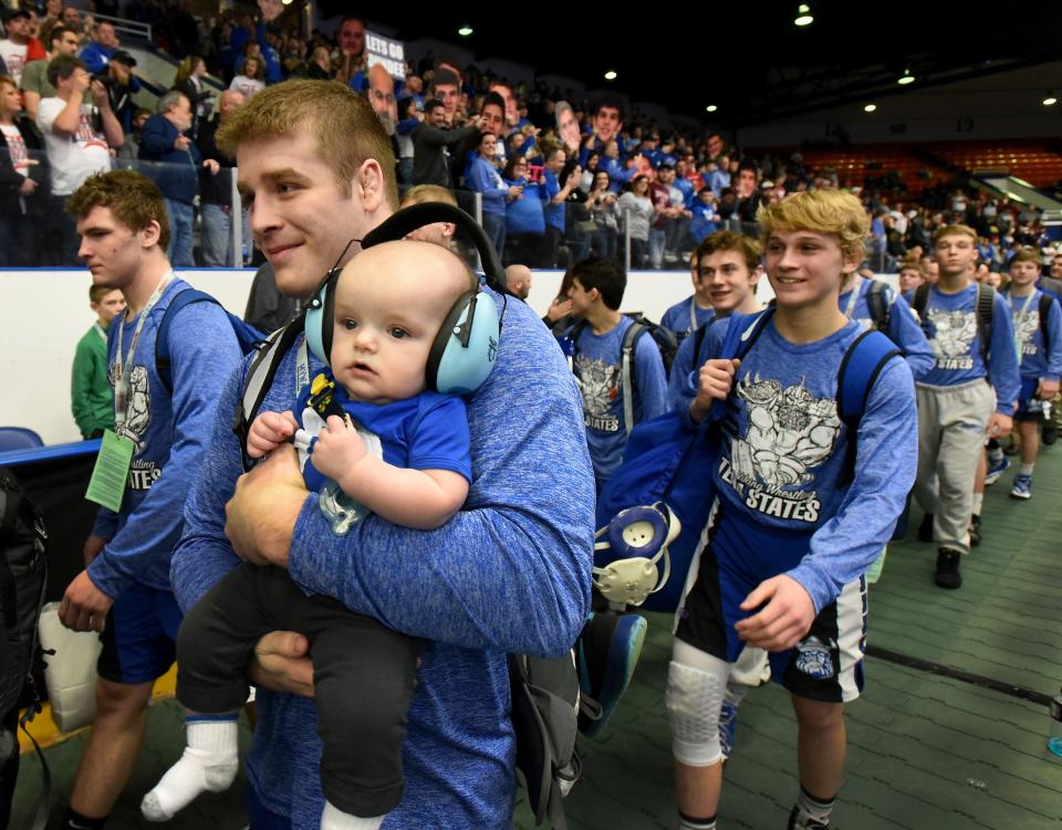 Dundee Vikings captain Brandon Whitman carries five-month-old Brady Stevens, the son of assistant coach Garrett Stevens as they take part in the grand march of the Division 3 team state semifinals at Wing Event Center in Kalamazoo 2018. The wrestlers have adopted Brady who has posed with the championship trophies this year.