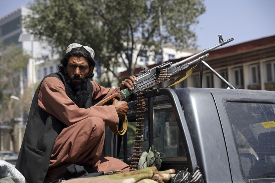 A Taliban fighter sits on the back of a vehicle with a machine gun in front of the main gate leading to the Afghan presidential palace, in Kabul, Afghanistan, Monday, Aug. 16, 2021. (Rahmat Gul/AP Photo)