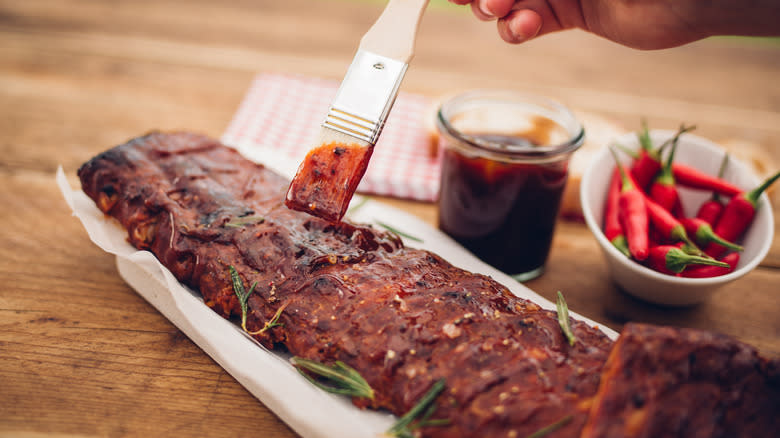 Someone brushing marinade onto meat