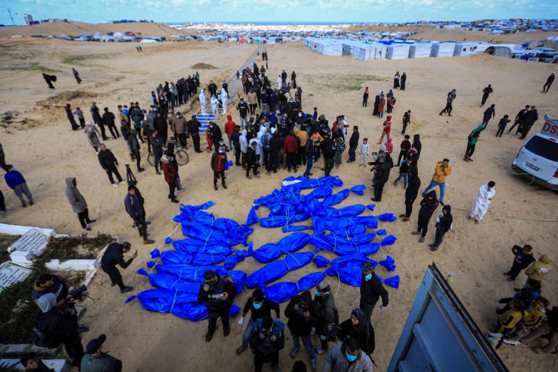 Palestinians bury the bodies of 80 Palestinians, who were handed over by the Israeli army through the Kerem Shalom border crossing, in a mass grave. Mohammed Talatene/dpa