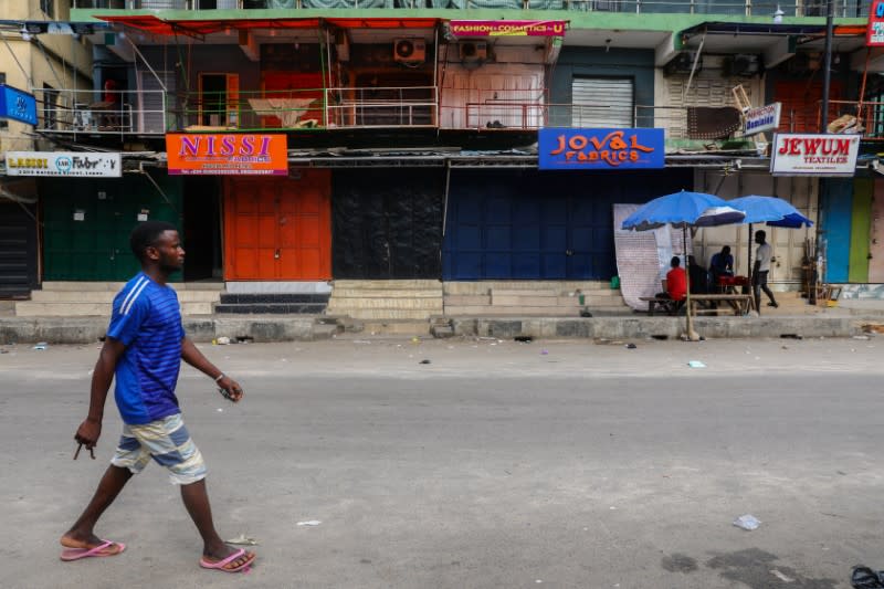 A man walks on the street beside closed shops in a nearly deserted wholesale market during lockdown by the authorities to limit the spread of coronavirus disease (COVID-19), in Lagos