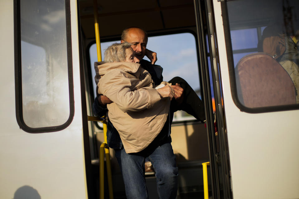 A woman is carried out of a bus with people who fled from Mariupol, Tokmak and Berdyansk as they arrive to a reception center for displaced people in Zaporizhzhia, Ukraine, Tuesday, May 3, 2022. Thousands of Ukrainian continue to leave Russian occupied areas. (AP Photo/Francisco Seco)