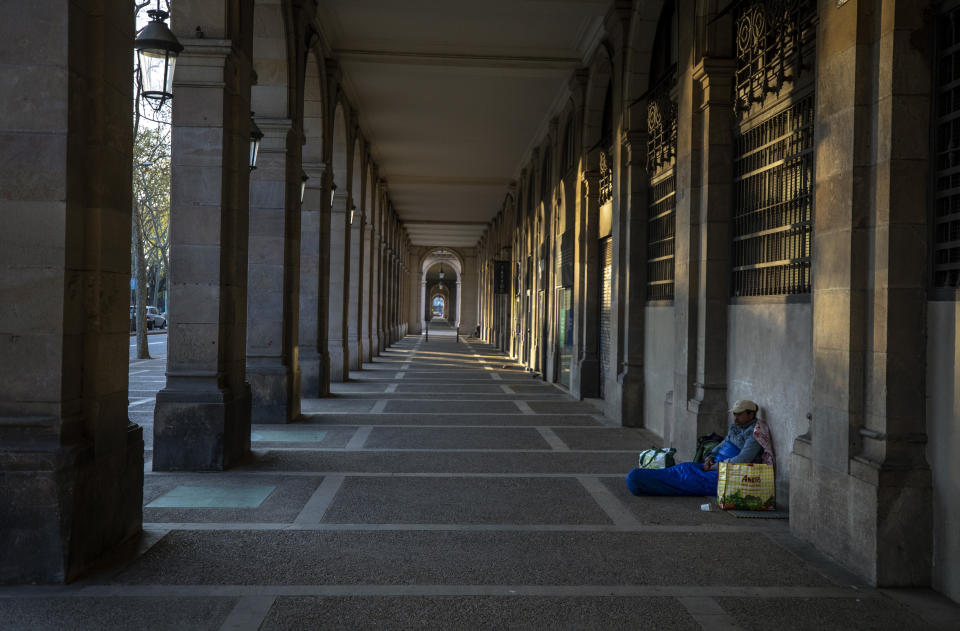 In this Friday, March 20, 2020 photo, Riccardo, 32, sits in empty arcades in downtown Barcelona, Spain. "I thought I had seen everything during all these years sleeping in the street, but no. This silence on the street all day scares me... more than the virus itself ..." says Riccardo, 32, who has been sleeping on the street for more than 10 years. (AP Photo/Emilio Morenatti)