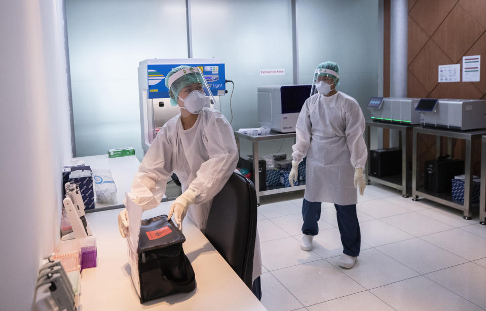 Laboratory staff members work for the COVID-19 virus testing at Suvarnabhumi Airport in Bangkok, Friday, July 3, 2020. As the country starts to ease its travel restrictions allowing foreign visitors in on a controlled basis, the lab will have the results ready within 90 minutes for arriving travelers. (AP Photo/Sakchai Lalit)