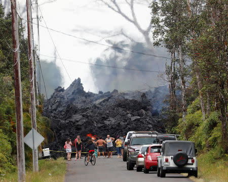 Onlookers gather in front of a fresh lava flow from the Kilauea volcano, in the Leilani Estates near Pahoa, Hawaii, U.S., May 26, 2018. REUTERS/Marco Garcia